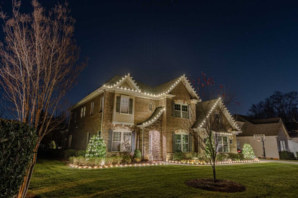 Holiday light installation with warm white rooflines and landscaping